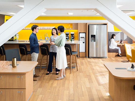 Three people talking in a modern kitchen and Coworking space