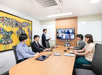 five people in a boardroom having a video conference
